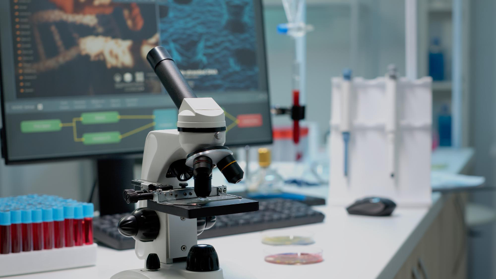 close up of chemical microscope and medical research equipment in scientific laboratory liquid examination tool with glass lens and blood samples in vacutainers on professional desk