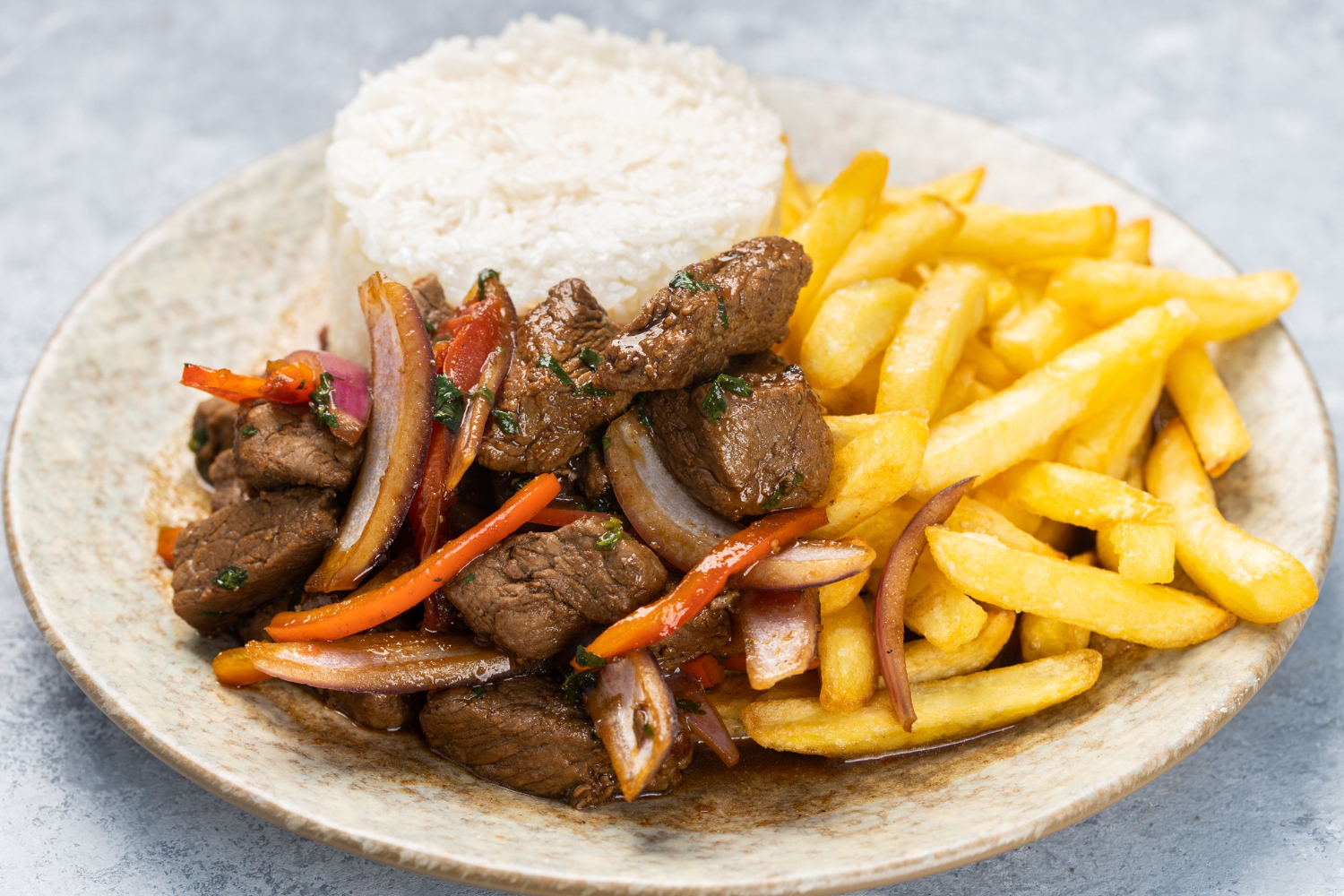closeup of roasted meat with sauce vegetables and fries in a plate on the table