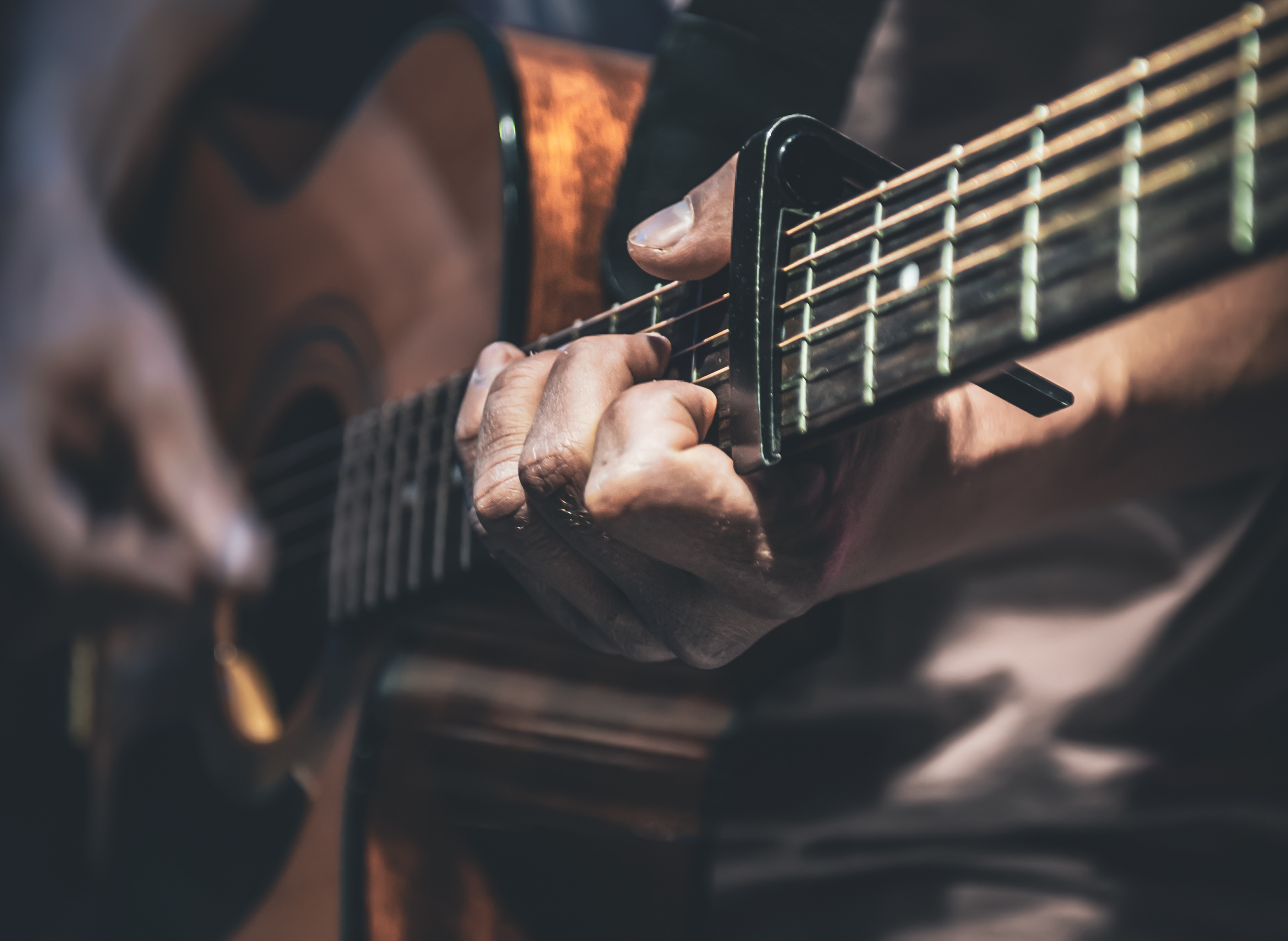 um homem toca uma guitarra acustica closeup 1