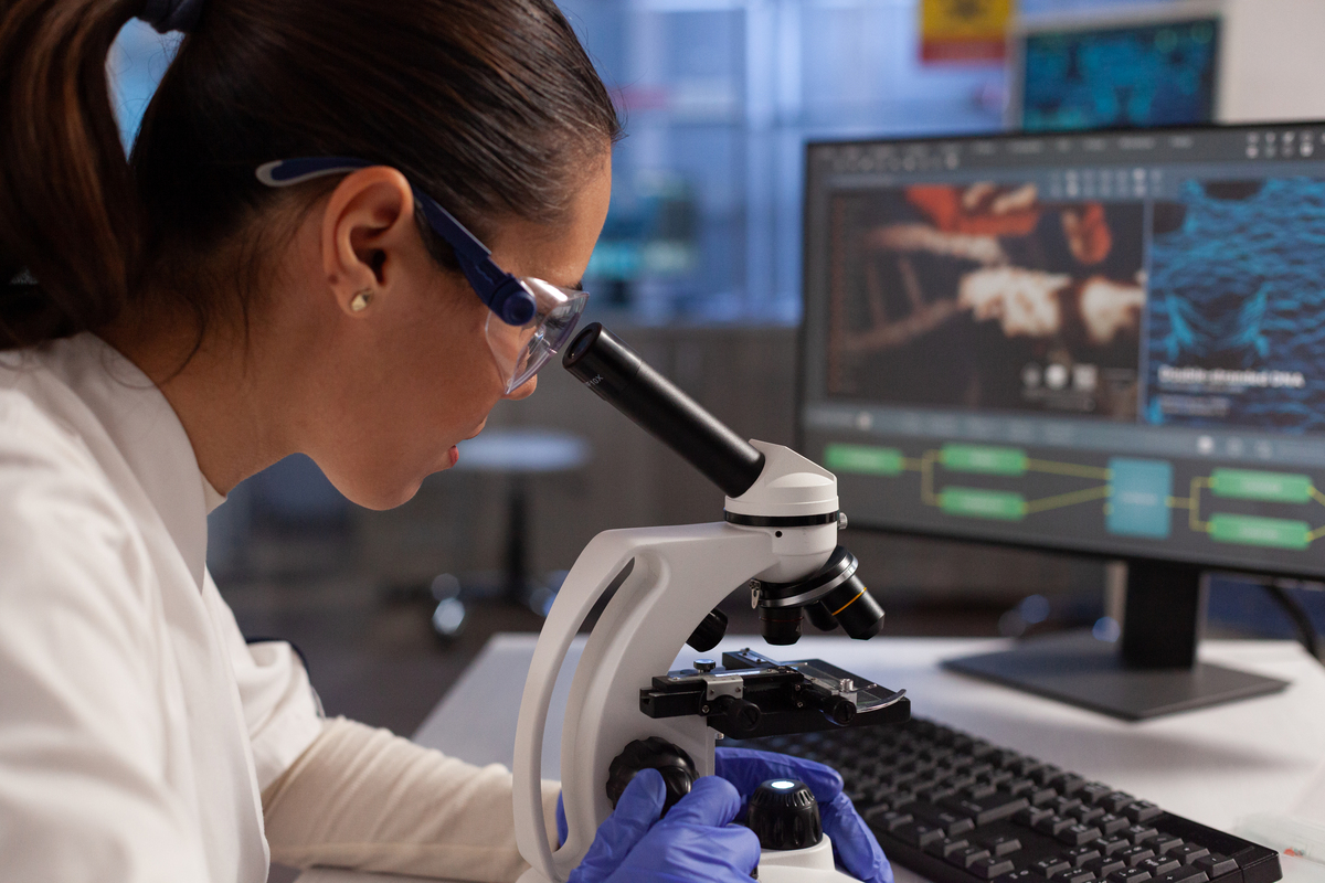 bioquimico trabalhando no microscopio para ilustracao de celula na tela computador no laboratorio de quimica mulher cientista analisando dna de virus tecido celular diagrama de plasma e nucleo de hemoglobina 1
